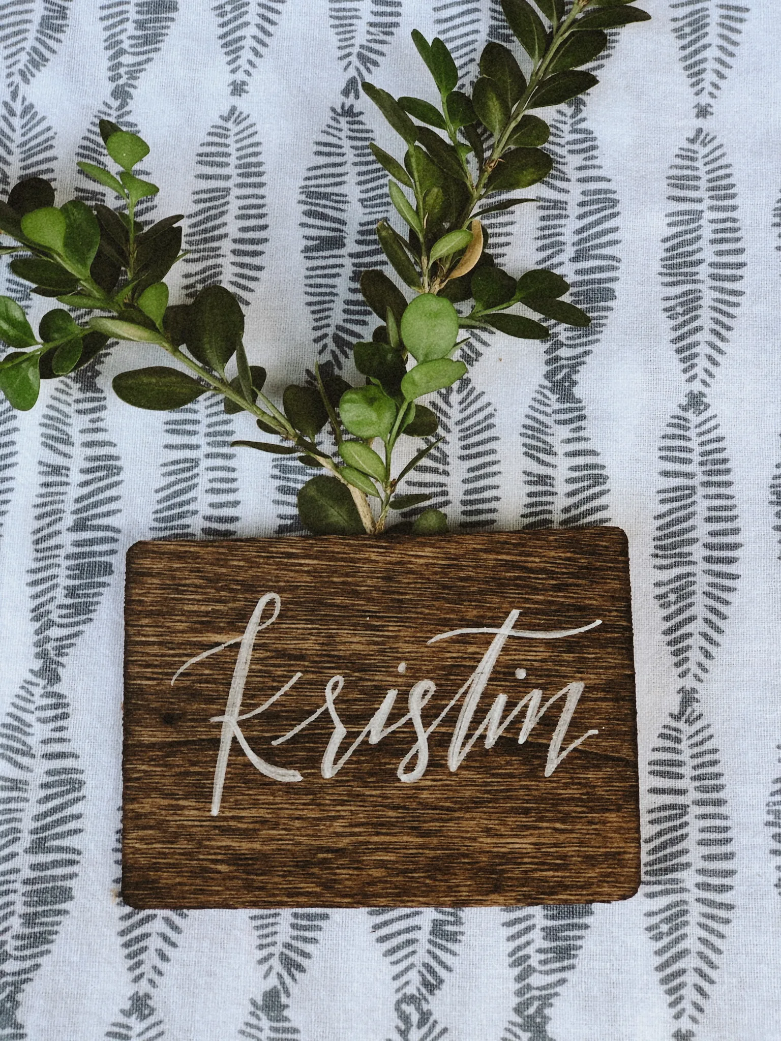 Wood calligraphy place card with greenery