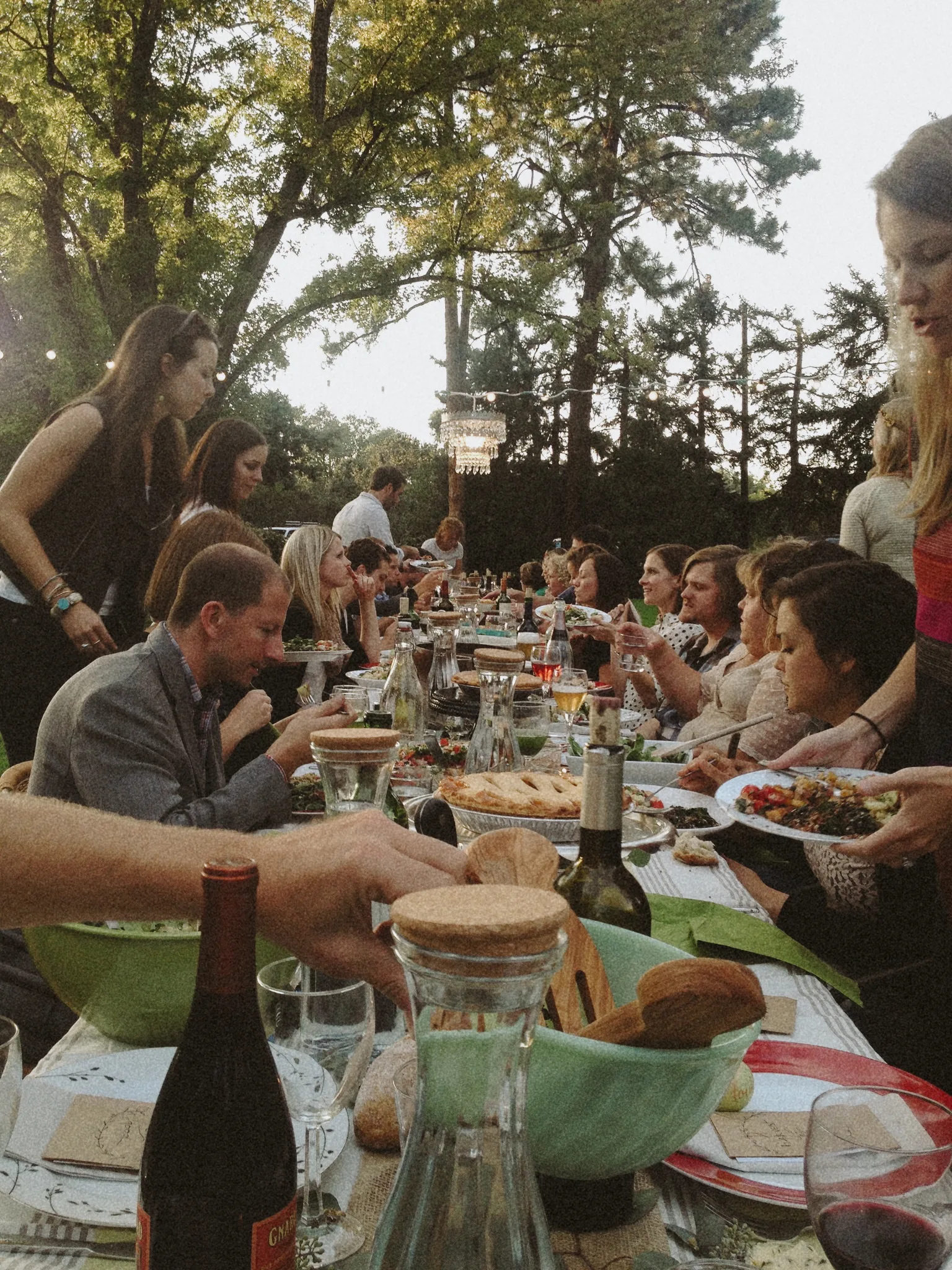 Guests serving food along a long outdoor table