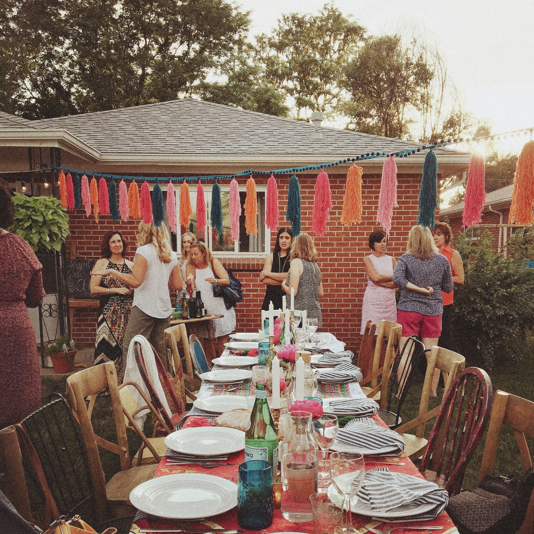 Guests gathered at an outdoor party with tassel garland